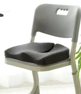 Dark gray coccyx cushion resting on a chair seat showing its real size and fit