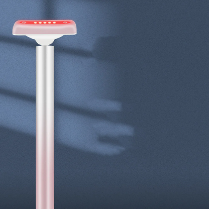 Rose-gold red light therapy wand with glowing red LED head on a calm blue background