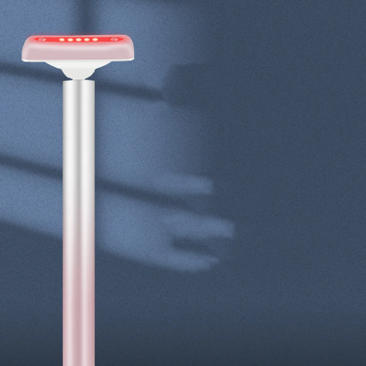 Rose-gold red light therapy wand with glowing red LED head on a calm blue background