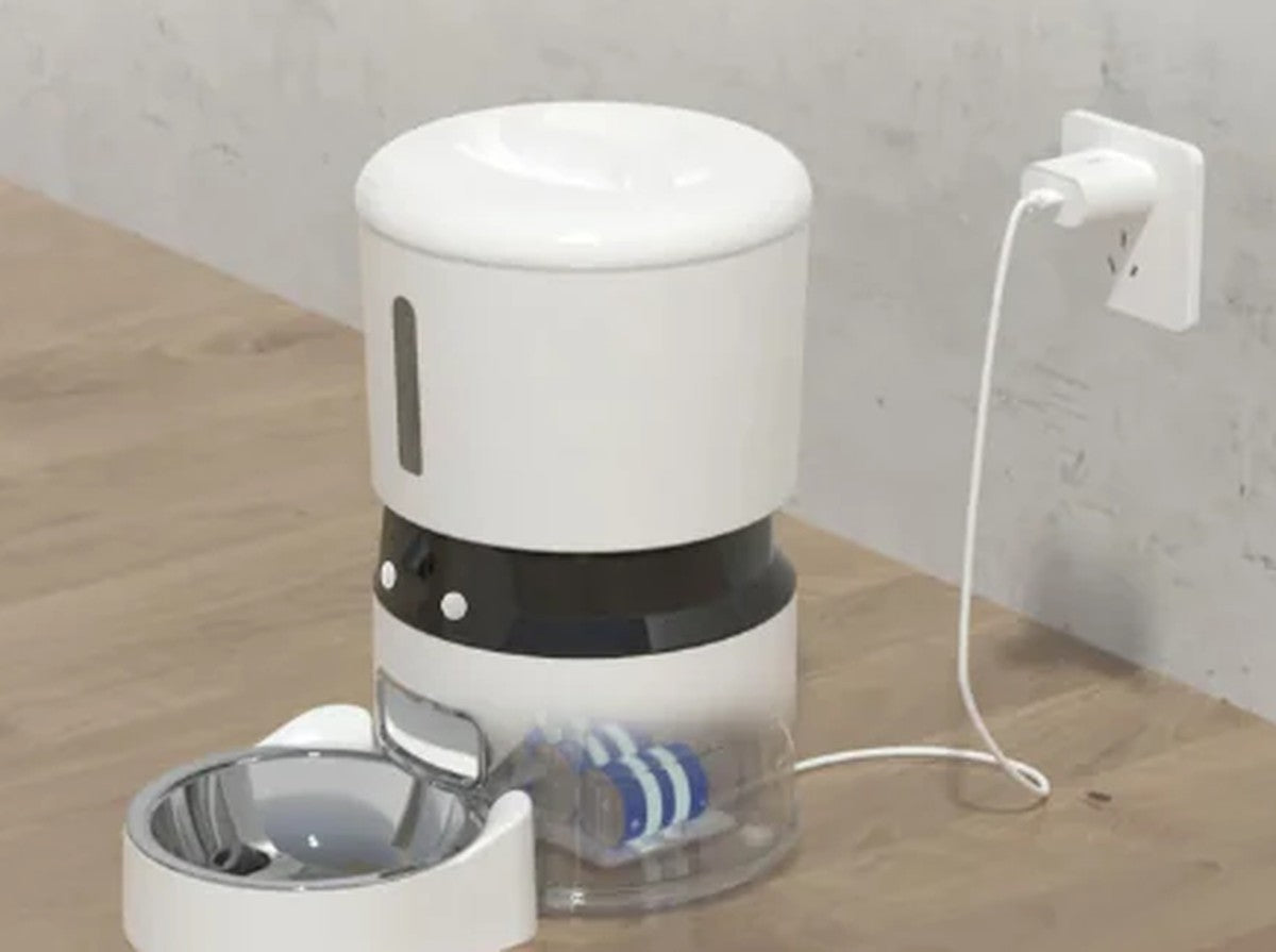 Cat feeder plugged into mains power with its transparent battery-backup base and stainless bowl, showing dual-power backup feeding