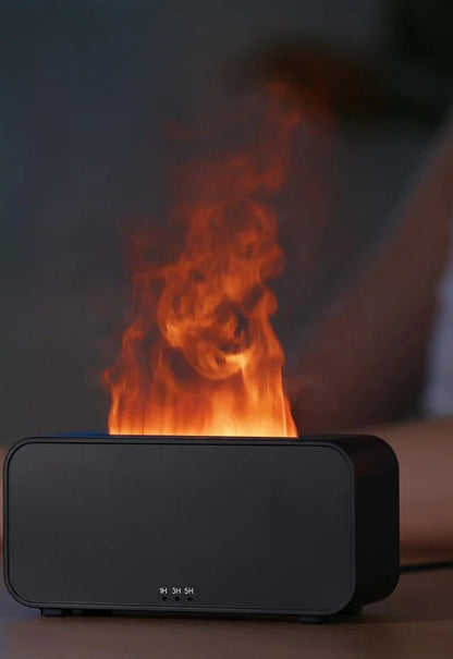 Black flame effect aromatherapy diffuser glowing with a realistic orange flame of backlit mist, 1H/3H/5H timer buttons visible on the front, in a dim bedroom.