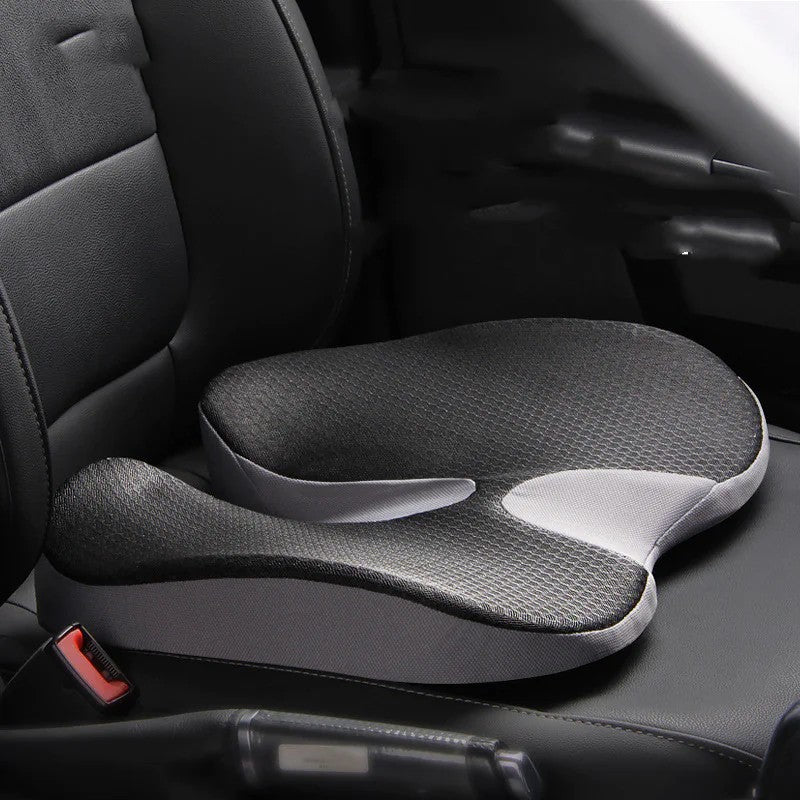 Black and grey memory-foam wedge car seat cushion with a U-shaped tailbone cutout, shown installed on a car seat ready for a long drive.