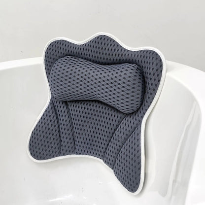 Grey 4D air-mesh bathtub pillow with a raised bone-shaped neck bolster and white piped trim, suction-mounted on the rim of a white bathtub.