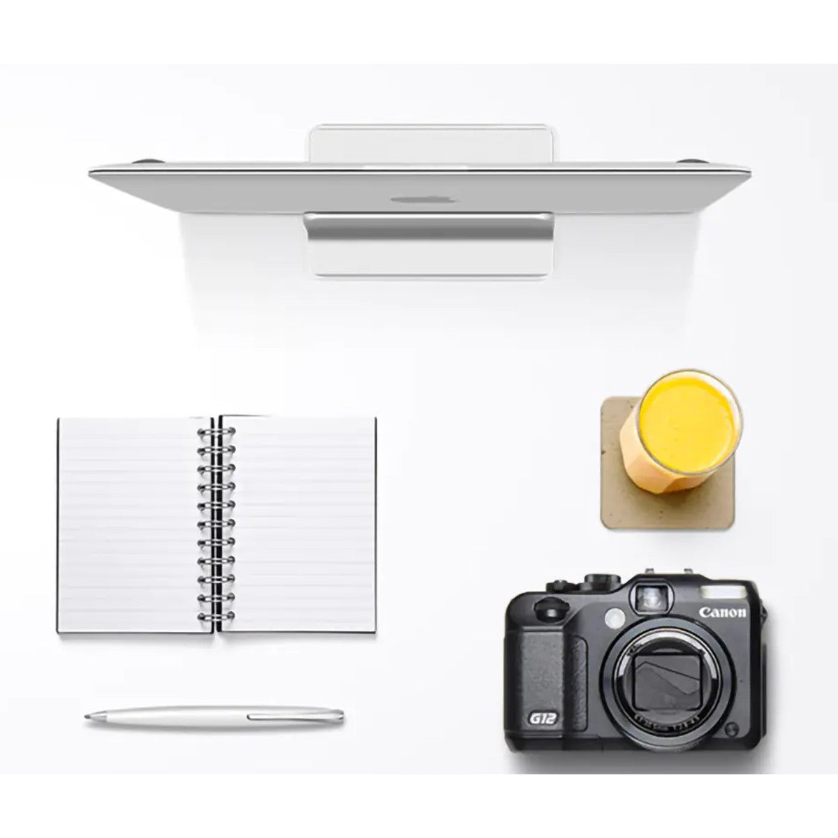 Overhead desk setup with the laptop stored upright in the stand beside a notebook and camera